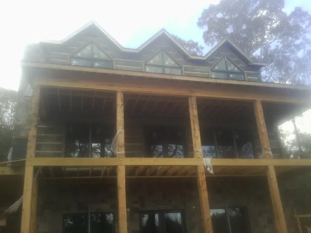 Dormers and porch framing on a large log home under construction — Roof Coating work by our crew in Branford
