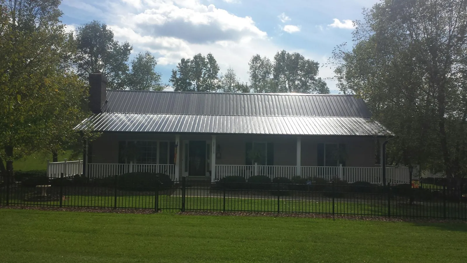 Gray metal roof on a brick ranch with a full width front porch — Gutter Guard Installation work by our crew in Branford