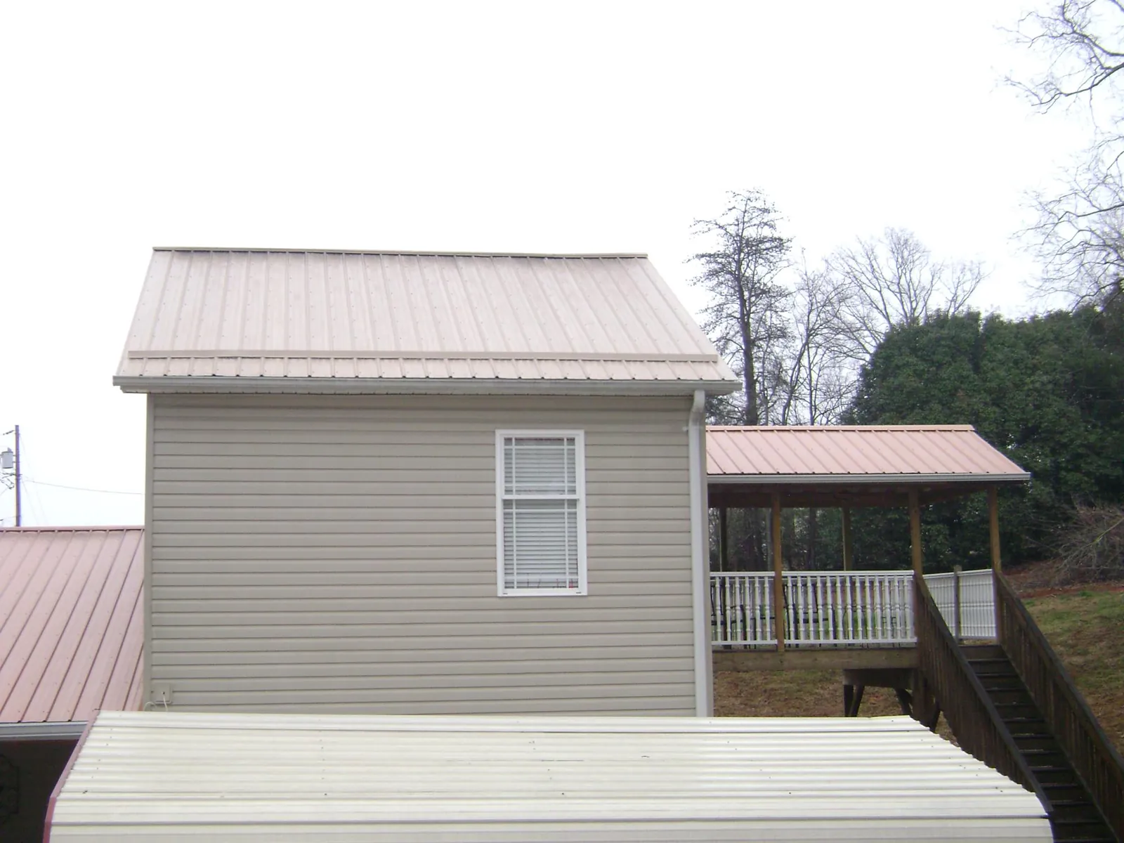 Tan metal roofs on a two story addition and attached porch, from a Roof Replacement job in Branford